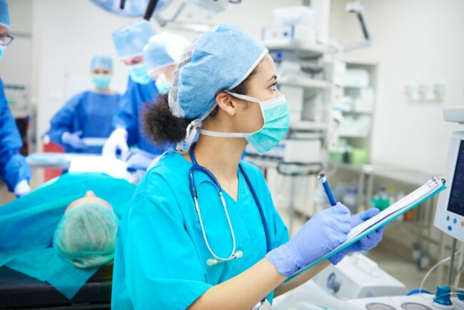 Woman in medical gear taking notes in a surgical room