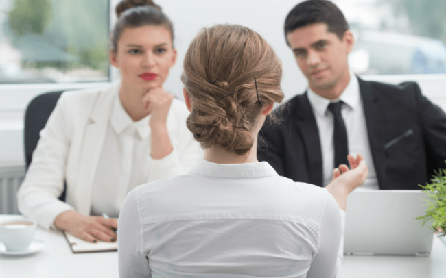 View of the back of a woman's head in an interview with another man and a woman