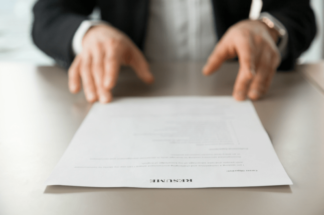 Close up of a man sliding a resume across a table